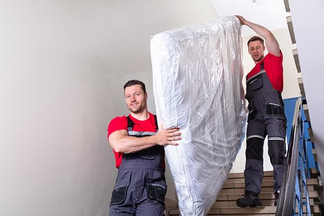 a heavy box spring being carried out of a house in Arlington